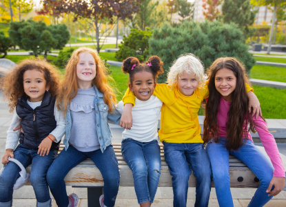 Interracial group of kids, girls and boys playing together at the park in summer day